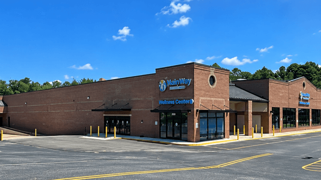 Exterior view of a brick wellness center with blue signage and clear sky