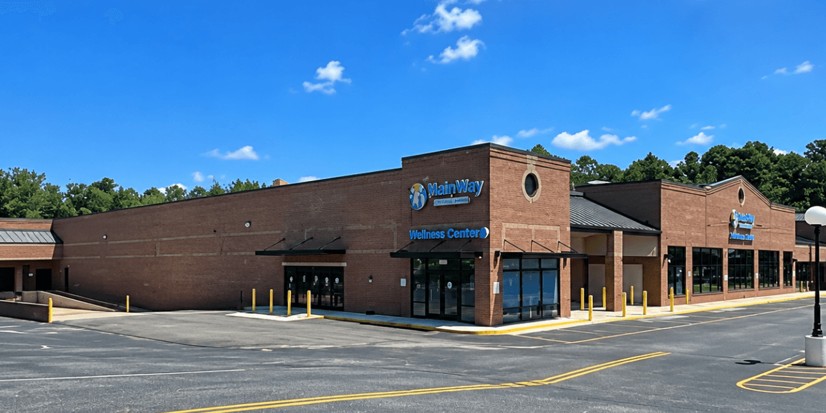 Exterior view of a brick wellness center with blue signage and clear sky