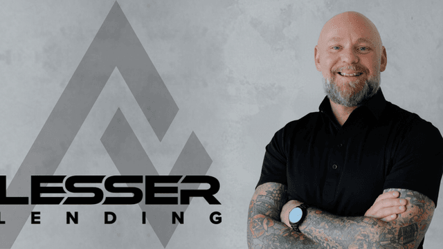 Smiling man with tattoos wearing a black polo shirt next to company logo