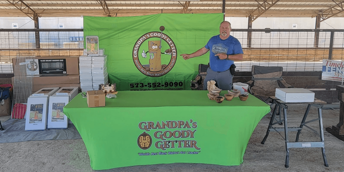A man stands at a table with a green tablecloth promoting Grandpa's Goody Getter