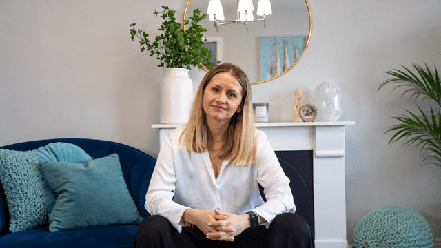 A woman sits on a blue couch in a stylish living room interior.
