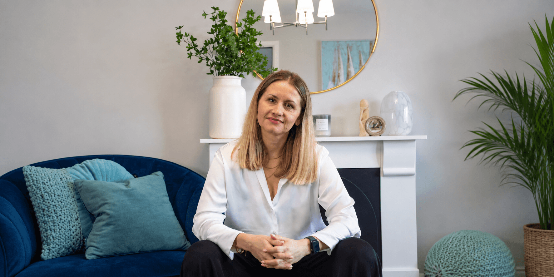 A woman sits on a blue couch in a stylish living room interior.