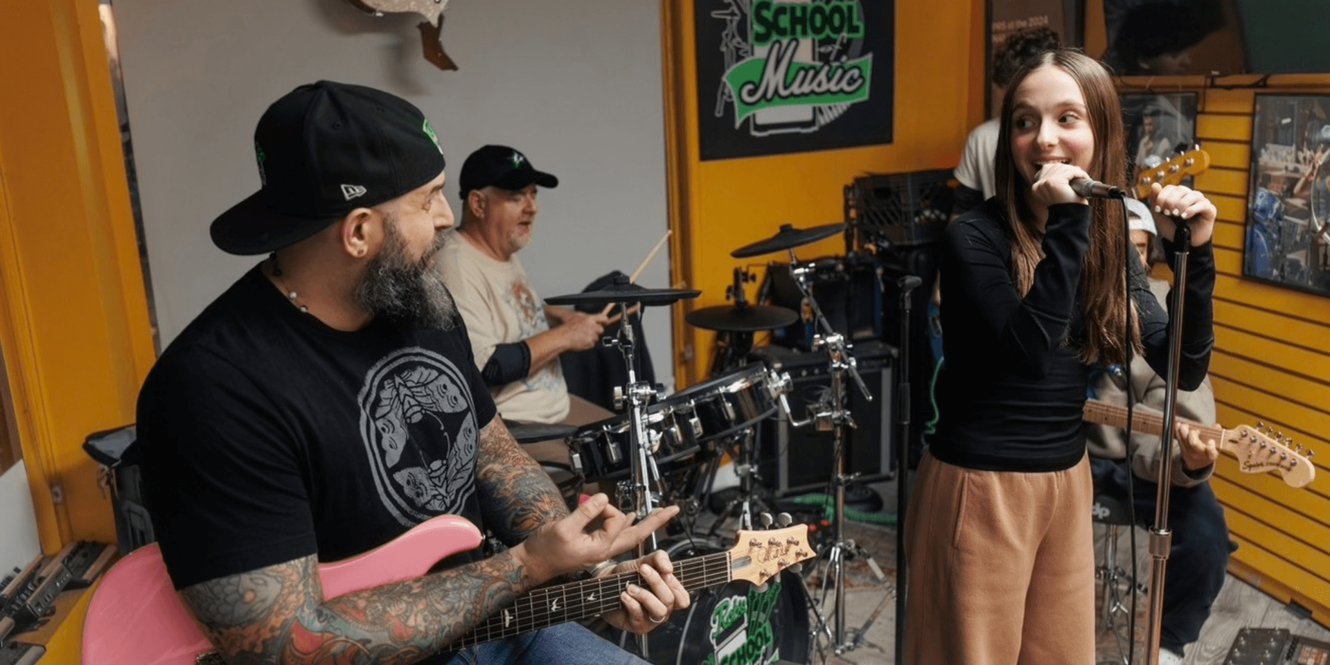 Band practicing in a music school; a girl sings while others play instruments