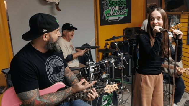 Band practicing in a music school; a girl sings while others play instruments