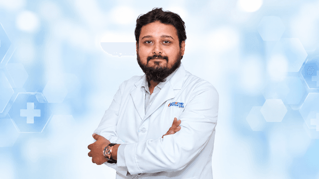 A man in a white lab coat poses confidently against a medical background