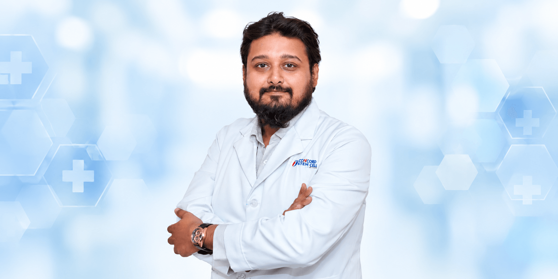 A man in a white lab coat poses confidently against a medical background