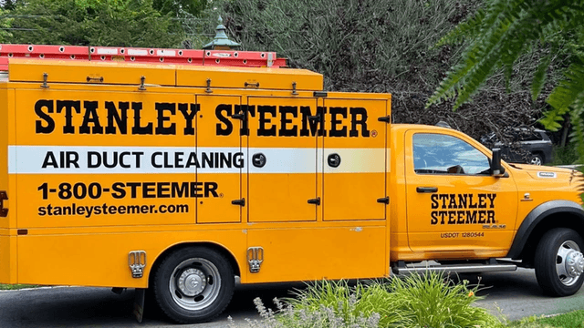 Bright yellow Stanley Steemer truck promoting air duct cleaning services parked on the street