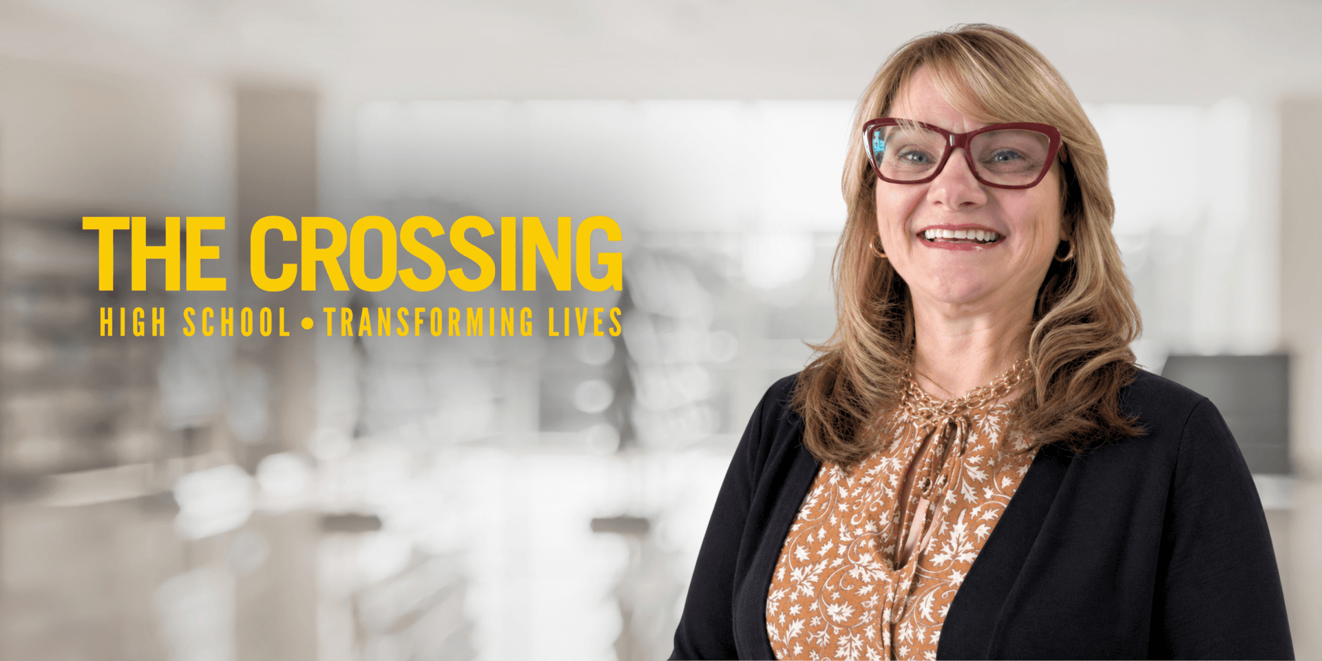 Smiling woman in a black jacket with glasses, promoting The Crossing High School