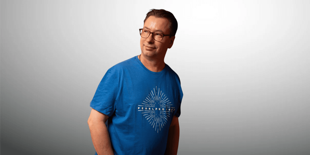 Man in a blue t-shirt stands confidently against a light gradient background