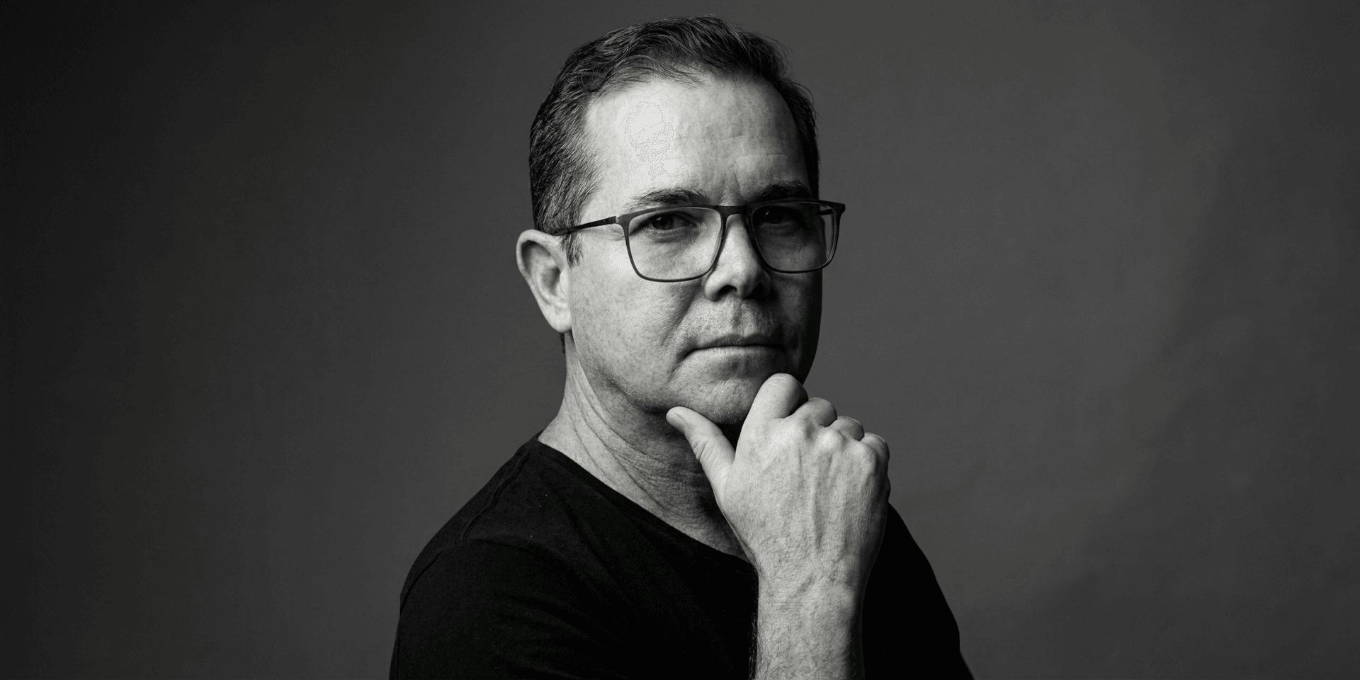 Black and white portrait of a man in glasses with a thoughtful expression