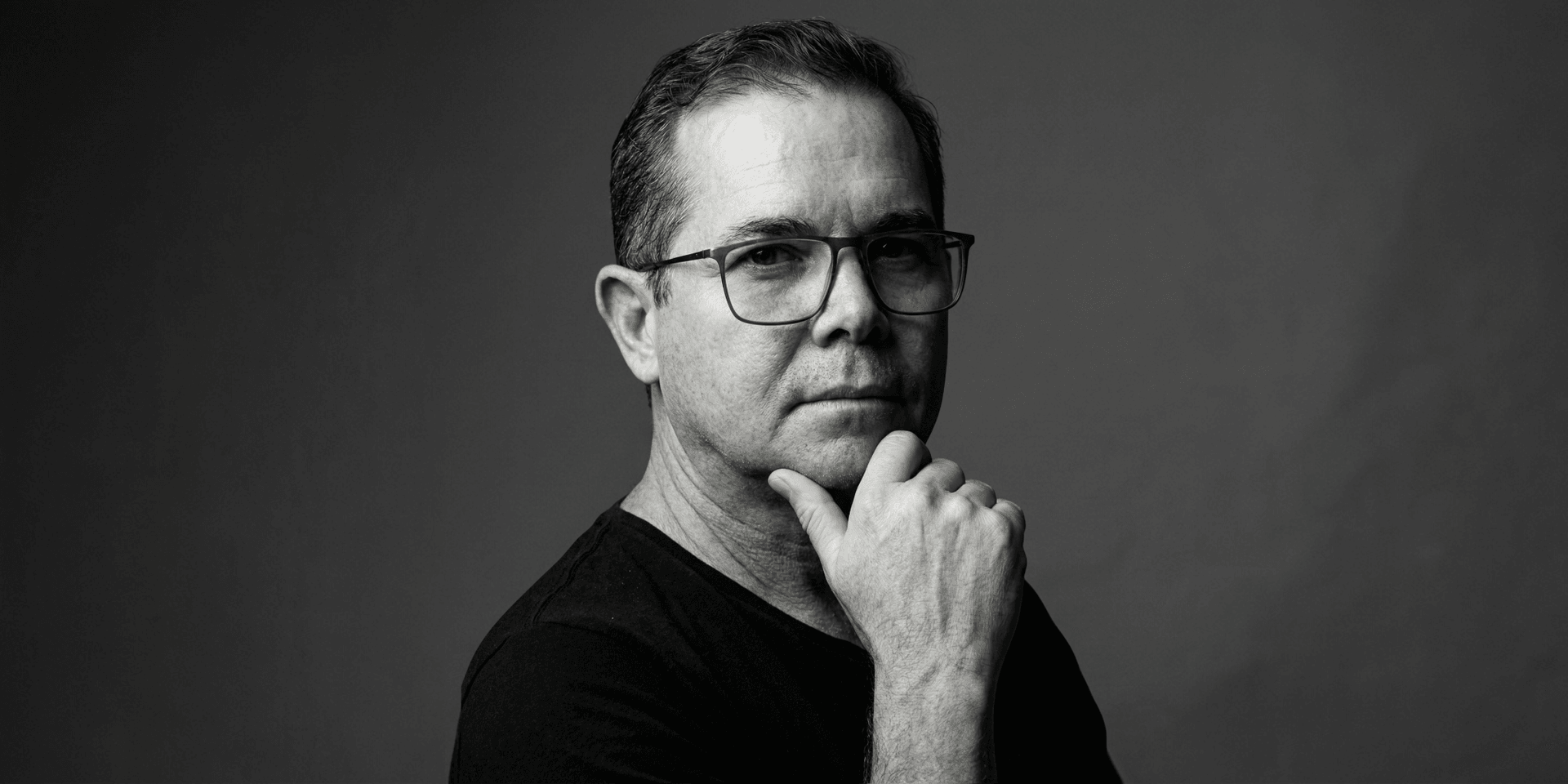 Black and white portrait of a man in glasses with a thoughtful expression