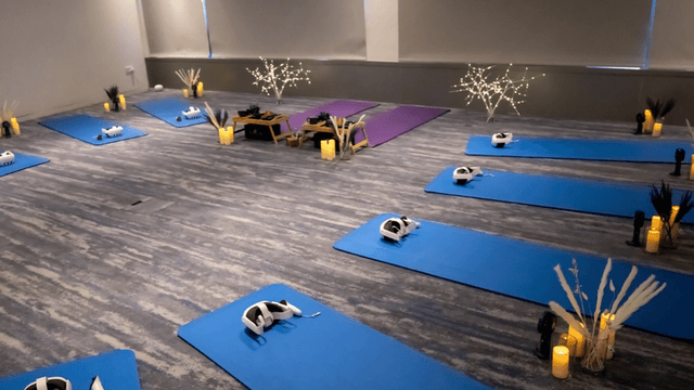 A serene yoga space with blue mats, virtual reality headsets, and soft lighting.