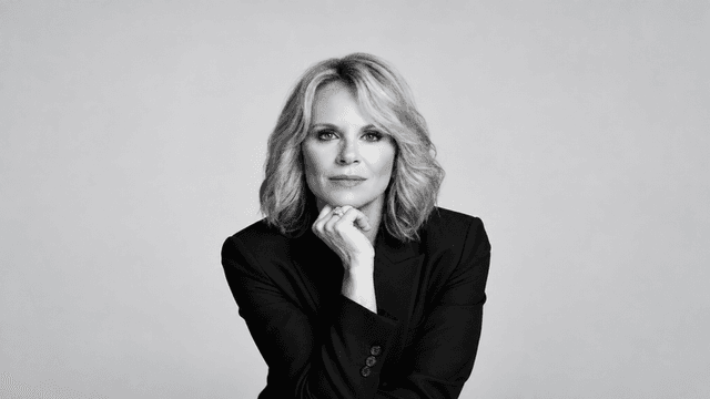Black and white portrait of a woman in a blazer, resting her chin on hand