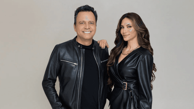 Two stylish individuals posed together in matching black leather outfits against a neutral background