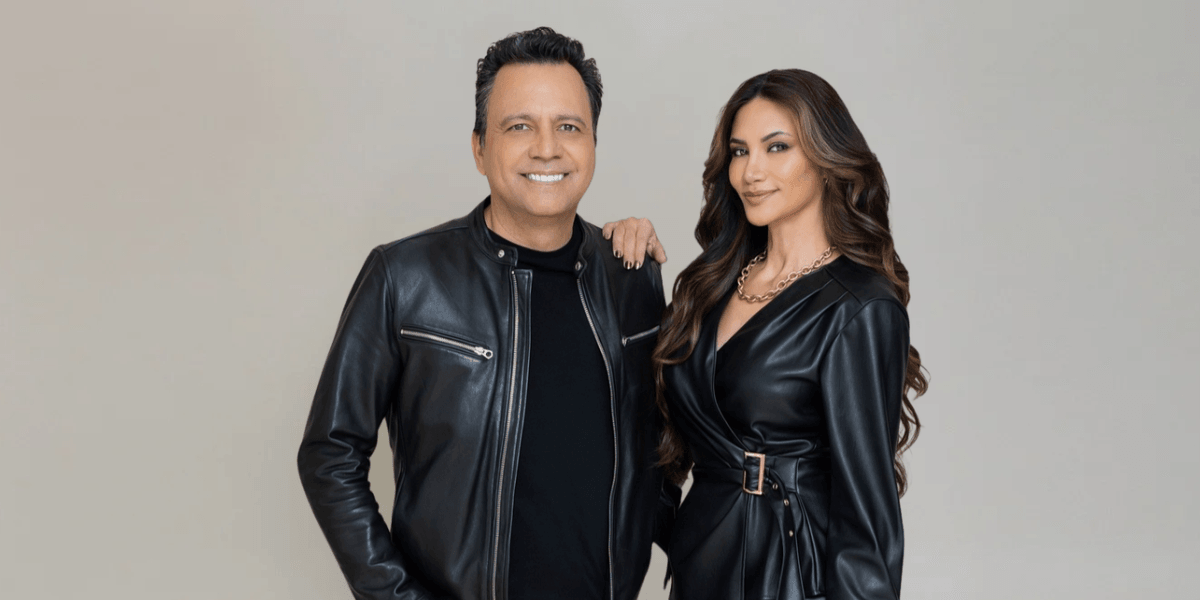 Two stylish individuals posed together in matching black leather outfits against a neutral background