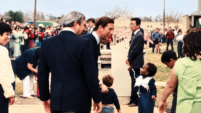 A gathering with people, including children, outdoors, smiling and interacting in a crowd.