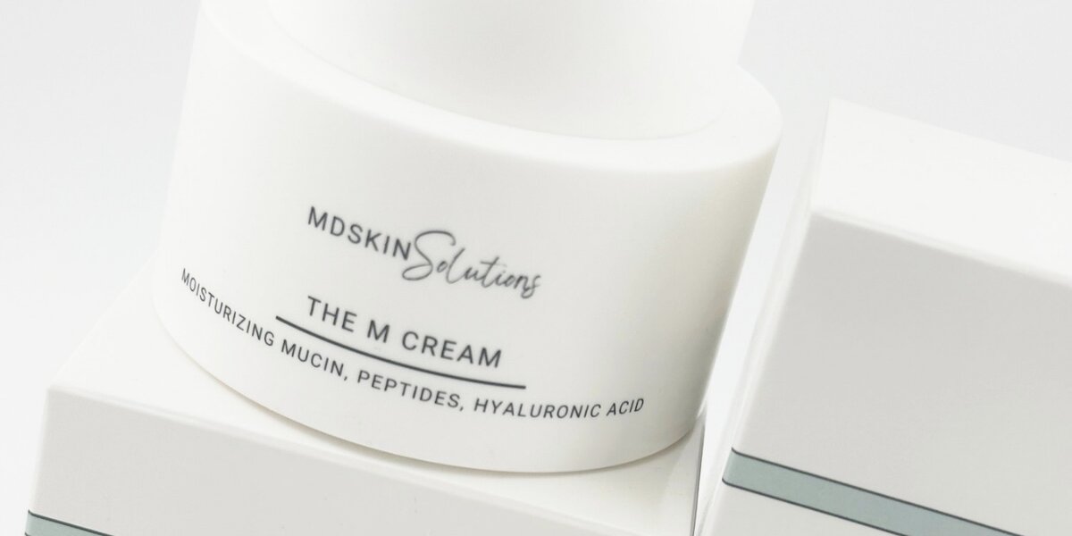 MD Skin Solutions The M Cream moisturizer highlighting peptides, hyaluronic acid, and moisturizing mucin formula.
