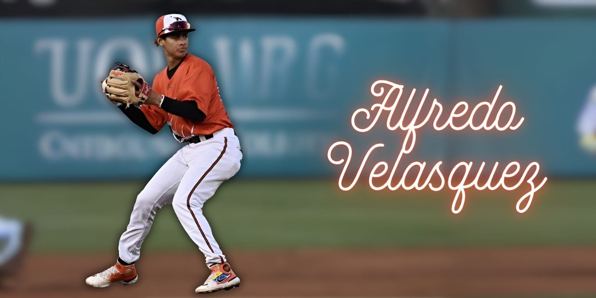 Baseball player Alfredo Velasquez in an orange Orioles uniform, winding up to throw with his name displayed on the right.