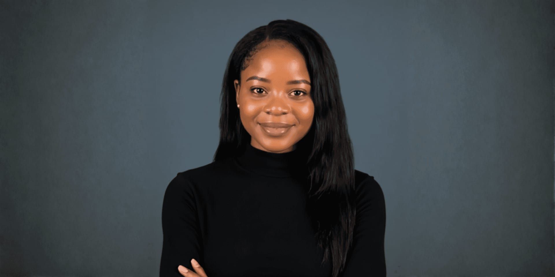 Portrait of a smiling woman in a black turtleneck against a gray background.