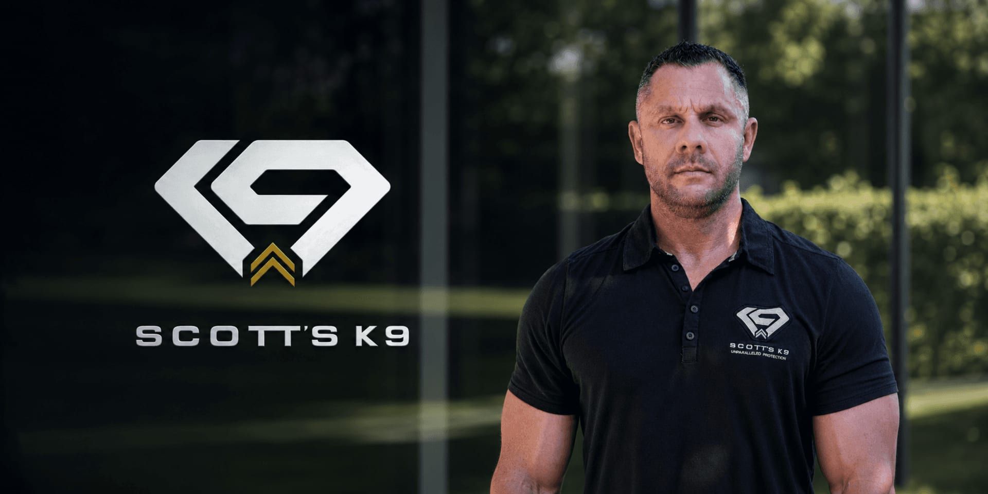 Steve Scott stands beside the Scott’s K9 logo wearing a branded black polo.