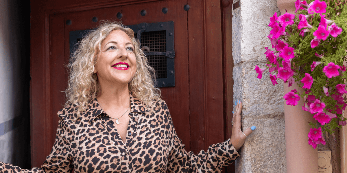 "Abigail Rebecca, a confident leadership mentor, standing outside with vibrant pink flowers, radiating authenticity and empowerment for women."