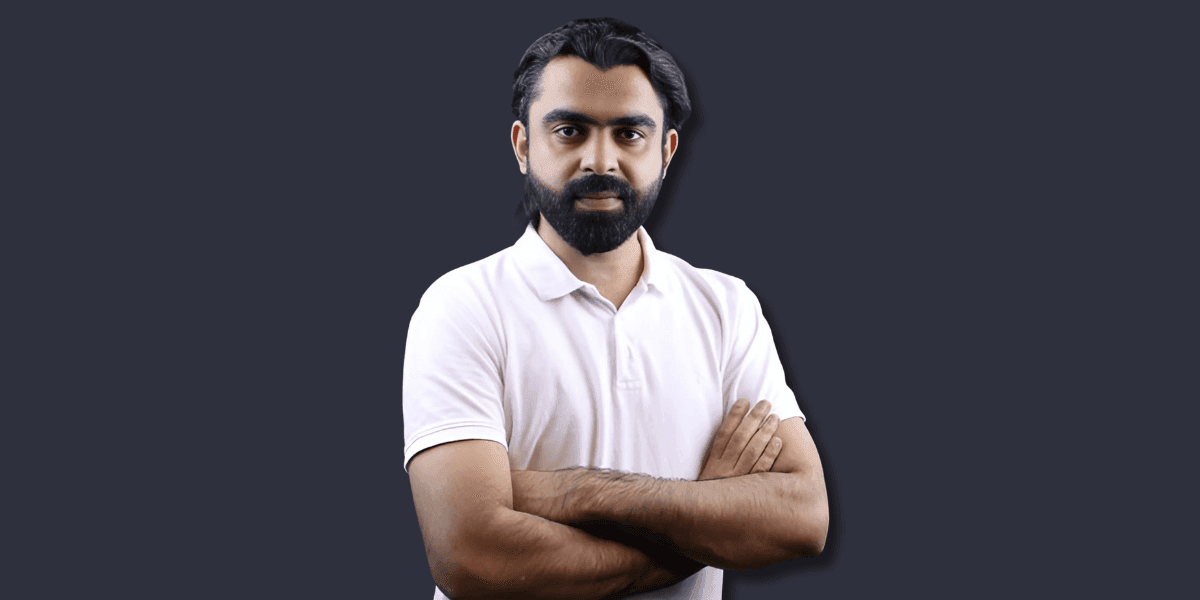 Confident professional man in a white polo shirt crossing his arms with a dark background.