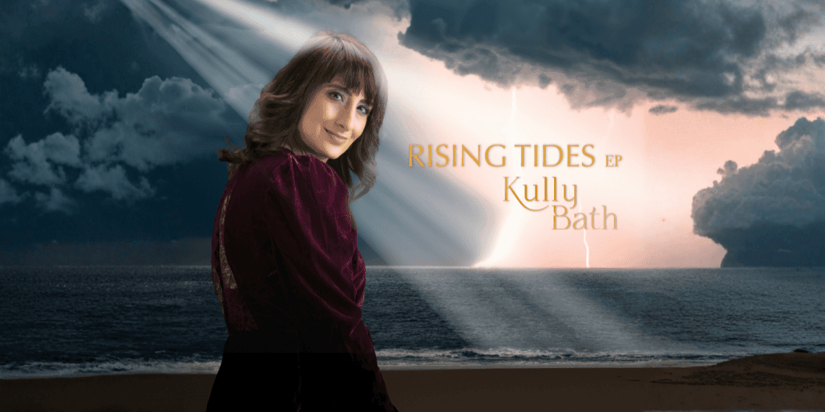 Kully Bath stands on a stormy beach beneath dramatic light rays, promoting her Rising Tides EP.