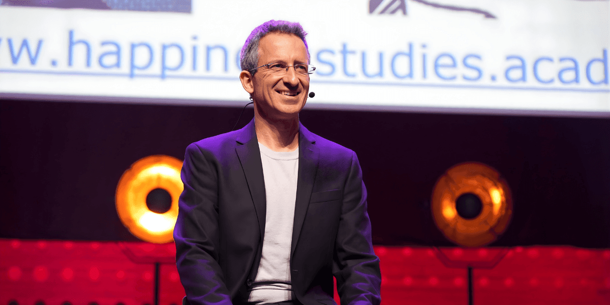 Dr. Tal Ben-Shahar, founder of the Happiness Studies Academy, speaking on stage about the SPIRE model for organizational wellbeing.
