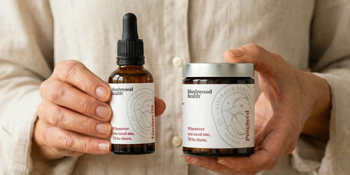 Two Blushwood Health products, a tincture and a jar, held by hands with labels featuring the brand's logo and slogan.