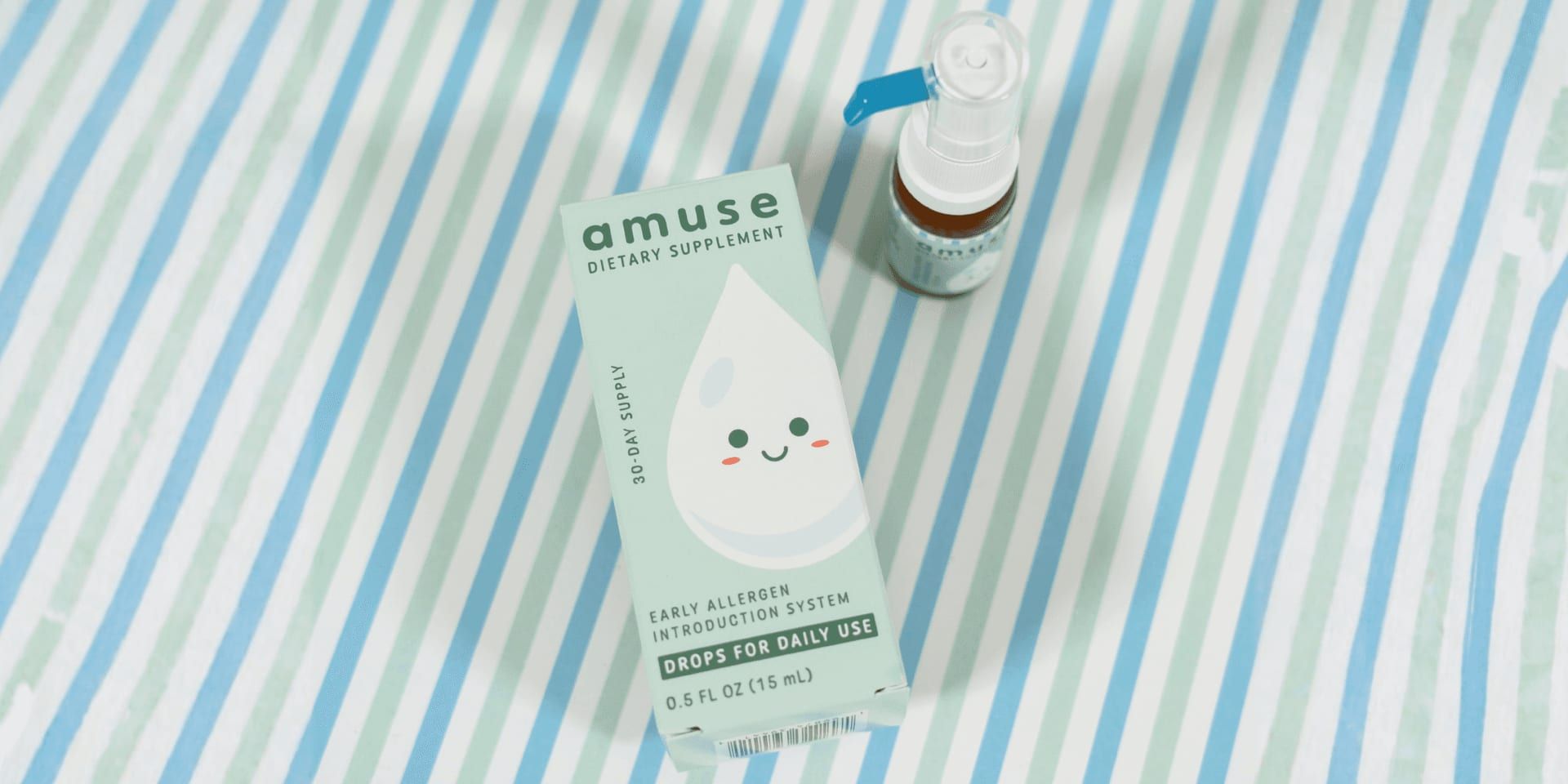 Amuse Drops product box and bottle displayed on a blue striped surface.
