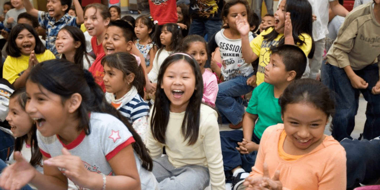 Group of children laughing and enjoying a fun activity in a classroom or event, showcasing diverse kids with bright expressions and engaging in a lively, joyful moment.