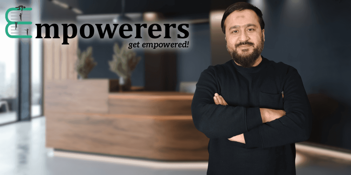 "Business owner or entrepreneur standing confidently with arms crossed, posing in front of a professional office space with Empowerers branding. The background features a modern workspace."