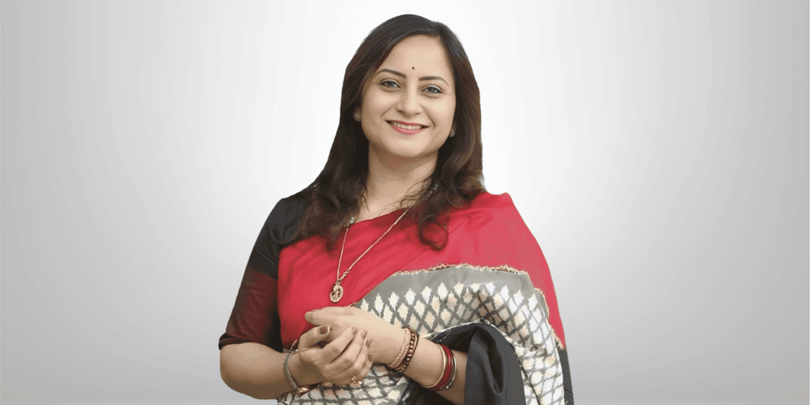 Prerana Patil, Founder & MD of INFINIA SCIENCES, wearing a red sari, smiling confidently in a professional setting.