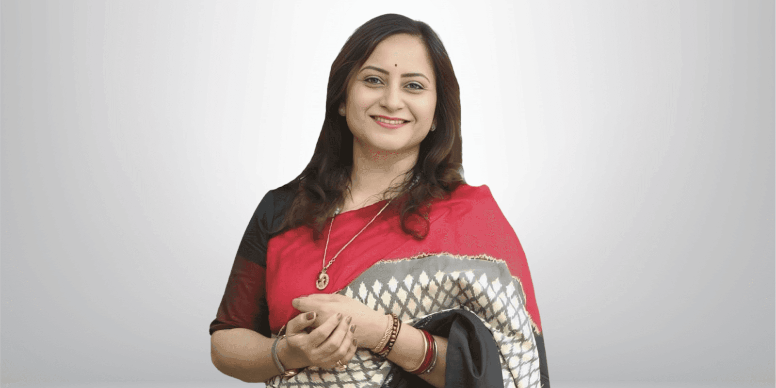Prerana Patil, Founder & MD of INFINIA SCIENCES, wearing a red sari, smiling confidently in a professional setting.