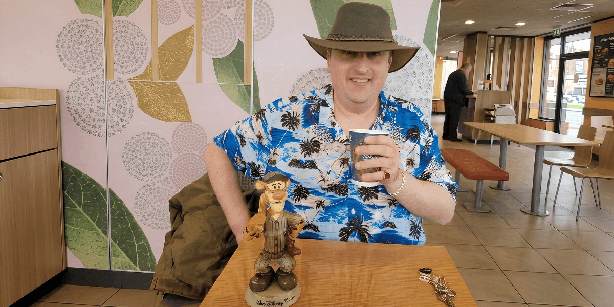 Jawad Sharief wearing a hat and patterned shirt while seated at a restaurant table holding a drink.