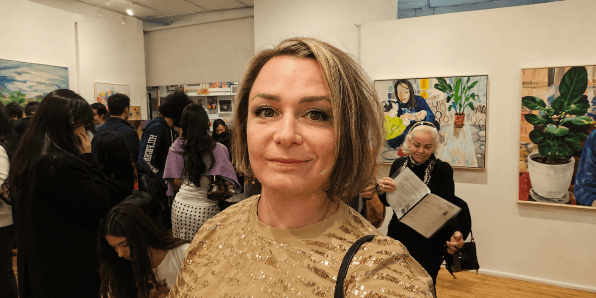 Contemporary artist Olha Svieshnikova at a crowded gallery exhibition featuring colorful paintings.