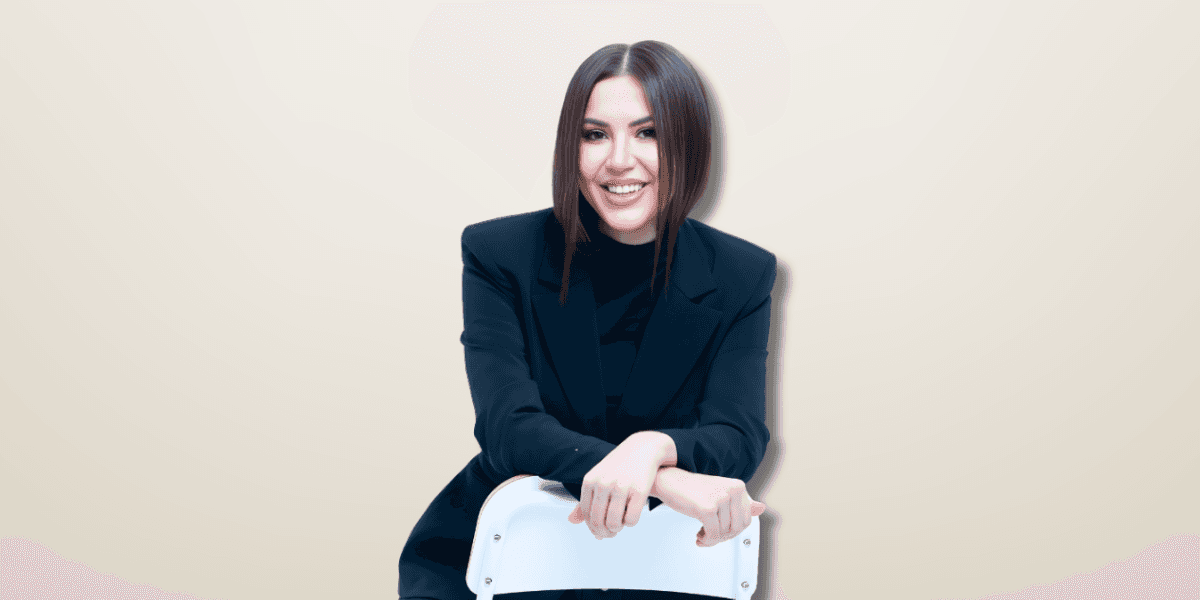 Georgiana Mart, a young, successful entrepreneur, smiles confidently while seated, showcasing her empowering, professional, and inspiring persona.