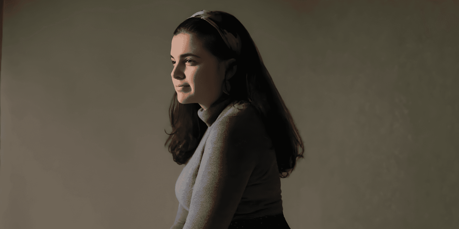 Carolina, a Portuguese-born pop-jazz vocalist, gazes thoughtfully with a serene expression, embodying the emotional depth of her music.