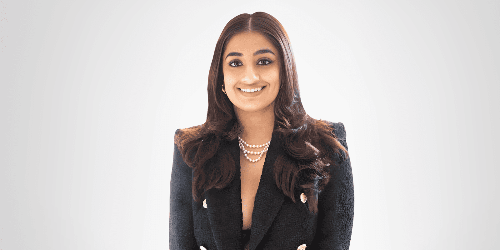 Dr. Meher Chahal smiling in a black blazer with pearls, representing her modern approach to business astrology.