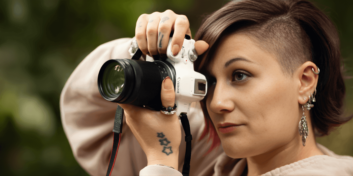 The image features Daniela Francella, a photographer, capturing a moment with her camera, embodying focus and artistry.