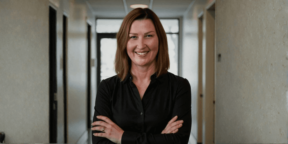 Renee West, founder of Intariq, smiles confidently in a hallway, symbolizing empowerment and human-centered AI for business owners.