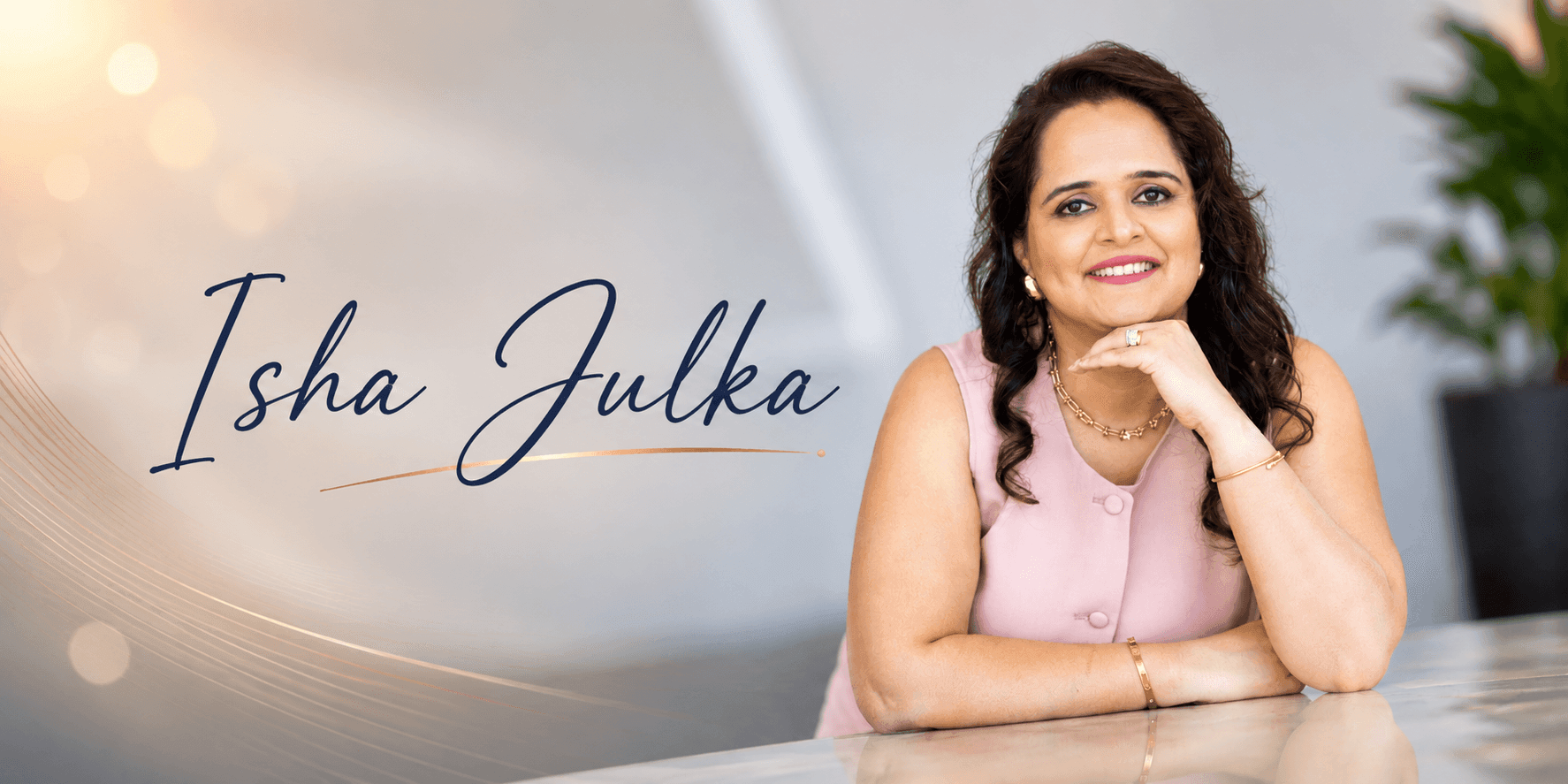 Professional portrait of Isha Julka smiling at a desk, with her name displayed on a soft, elegant background.