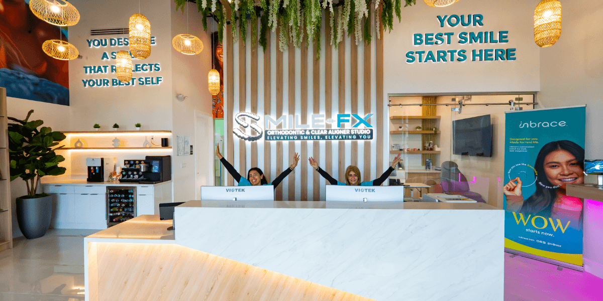 Reception area of SMILE-FX® orthodontic studio with staff smiling behind the front desk.