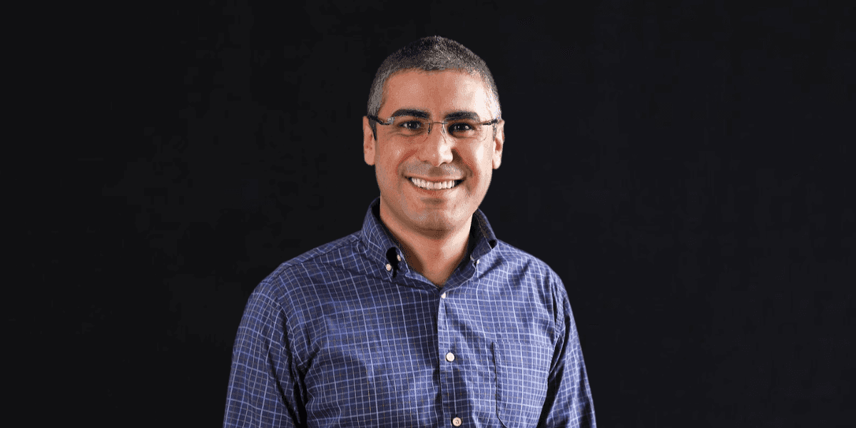 Portrait of entrepreneur and business coach Jad Atwe smiling against a black background.