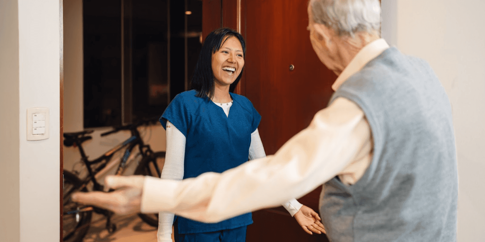 A caregiver greets an elderly client with warmth, embodying the importance of in-home nursing services for senior stability.