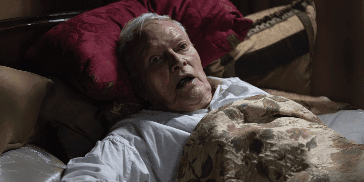 Elderly man with frightened expression lies in bed, hinting at supernatural horror in *Borley Rectory: The Awakening*.