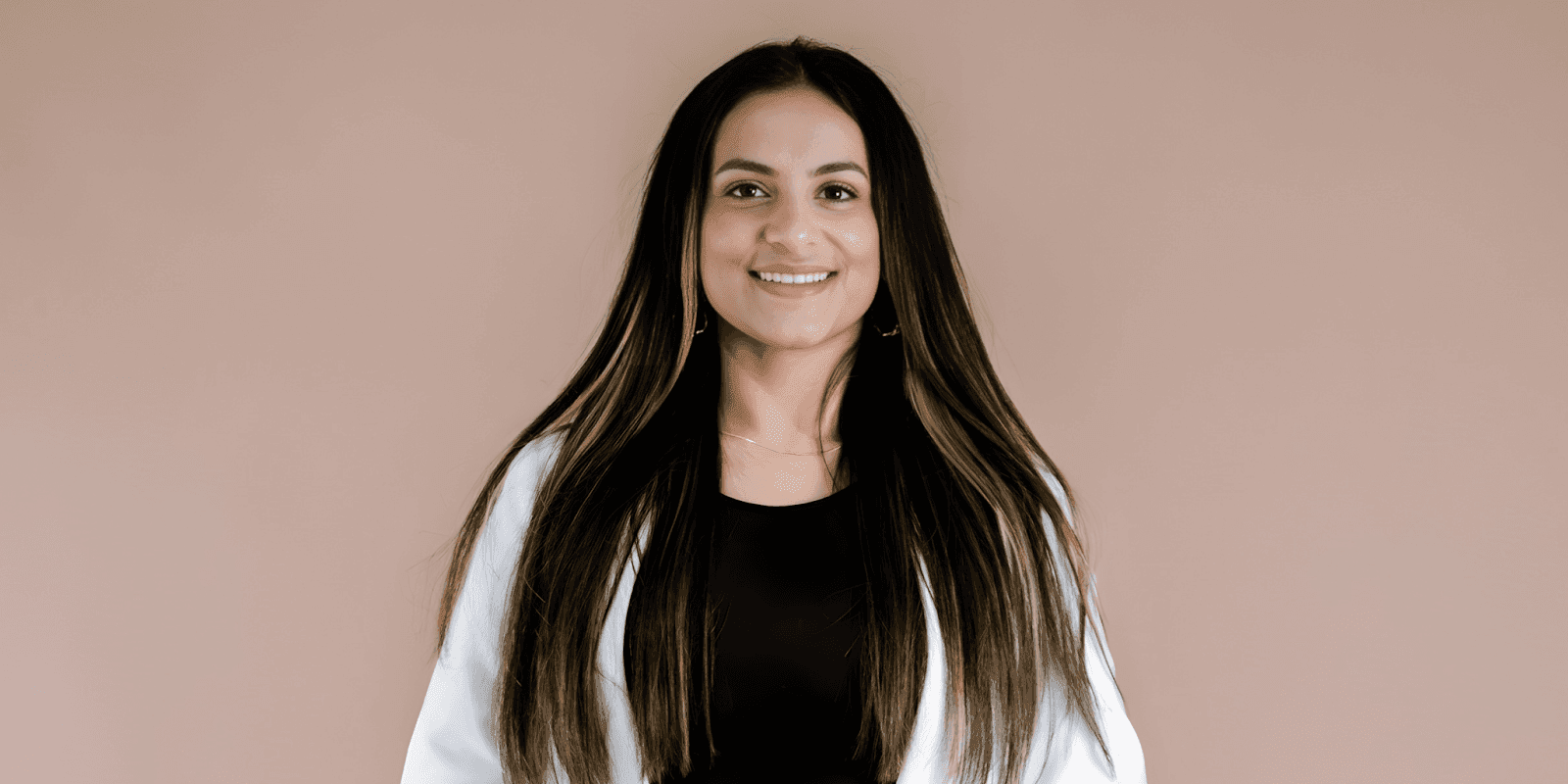 Aneeqa Mahmood, UGC creator and trauma therapist, smiling in a professional, warm pose against a simple neutral background.