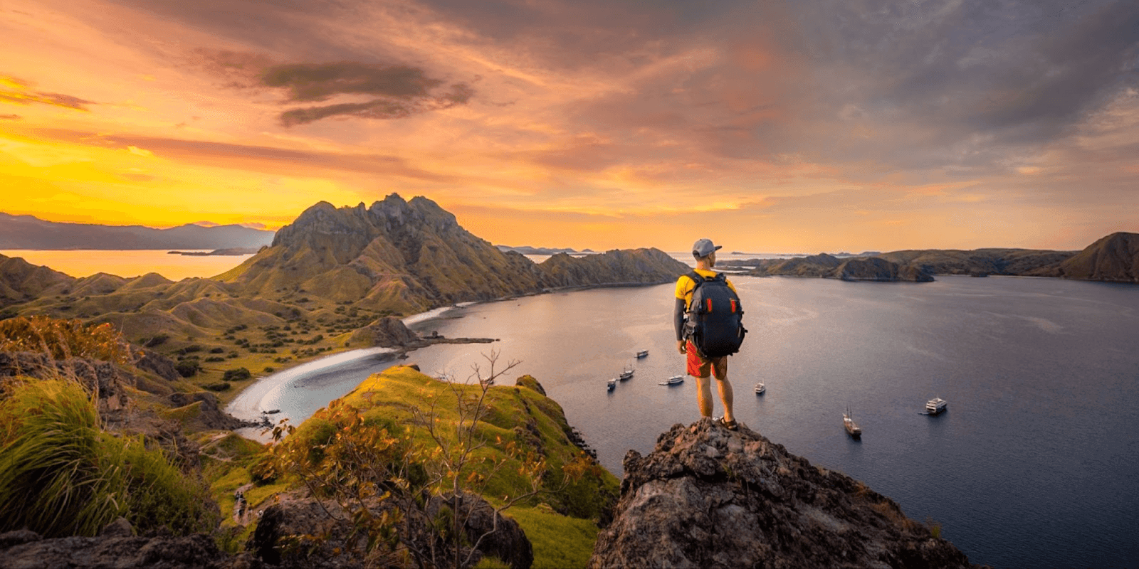 Photographer hiking through stunning landscape with Two Red Tabs backpack for travel and adventure photography.