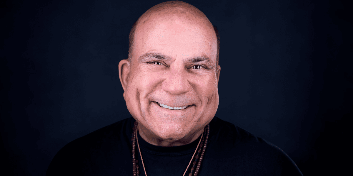 Dr. Joe Vitale, motivational speaker and filmmaker, smiling with confidence, embodying his transformative journey from homelessness to success.