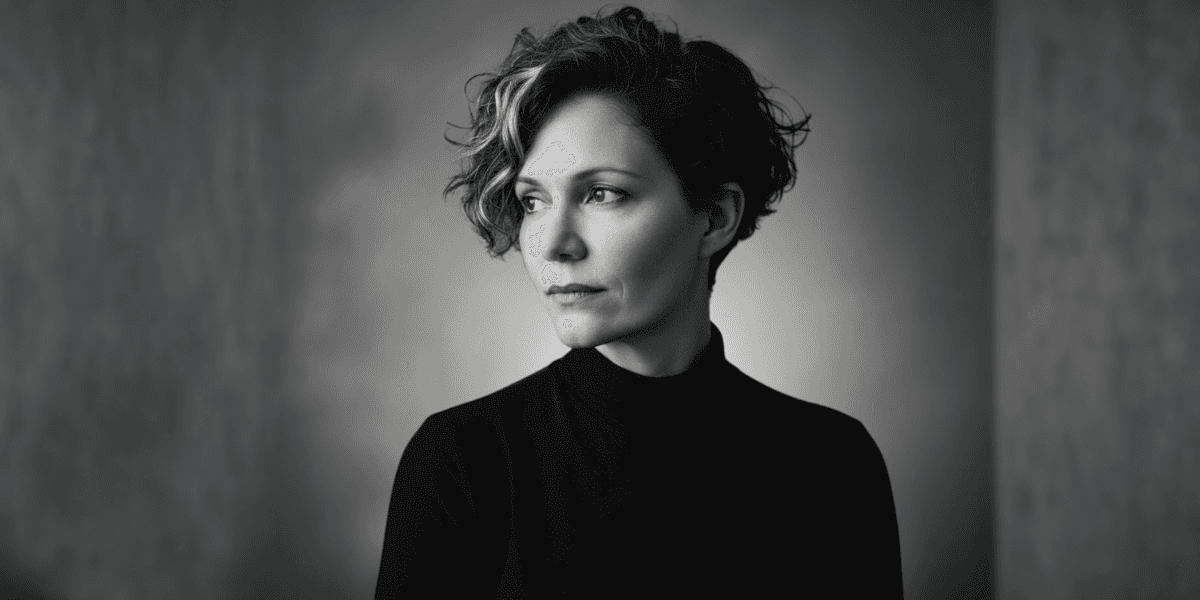 A woman with short curly hair, gazing thoughtfully, embodying clarity and inner strength.